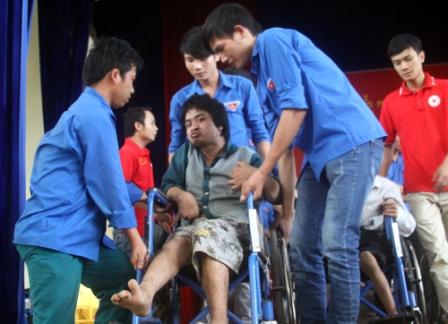 Các tình nguyện viên giúp người khuyết tật, nạn nhân chất độc da cam nhận xe lăn từ các nhà hảo tâm (ảnh: AT)