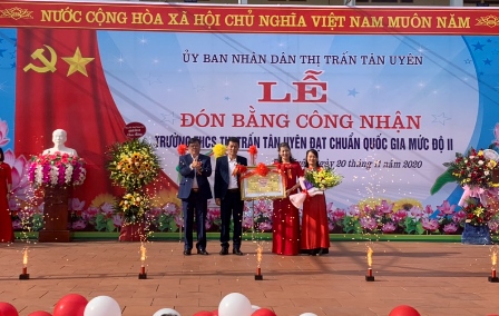 Đại diện lãnh đạo Huyện ủy, UBND thị trấn tặng hoa và trao Bằng công nhận đạt chuẩn quốc gia mức độ II cho Trường THCS thị trấn Tân Uyên.