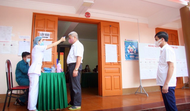 Kiểm tra thân nhiệt trước khi bầu cử tại khu vực bỏ phiếu số 2, thị trấn Than Uyê