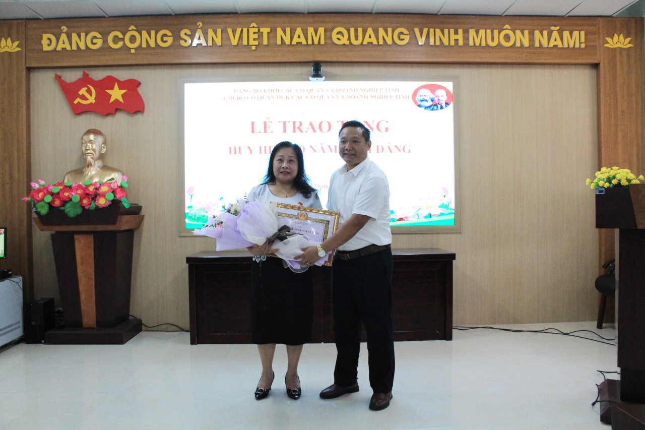 Đồng chí Lý Công Hà - Phó Bí thư Đảng ủy Khối các cơ quan và doanh nghiệp tỉnh trao Huy hiệu 30 năm tuổi Đảng và tặng hoa chúc mừng đồng chí Phan Thị Hà